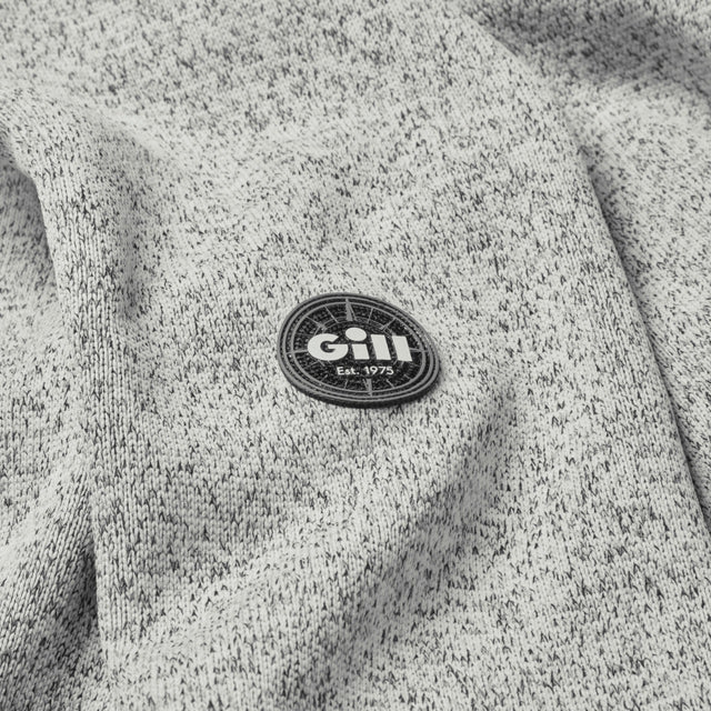 Close-up of a gray textured fabric with a Gill logo patch.