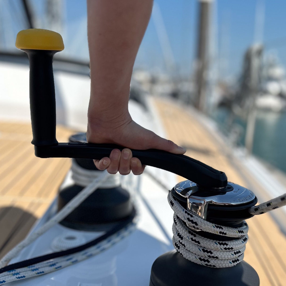 Hand holding a boat anchor handle with a marina background