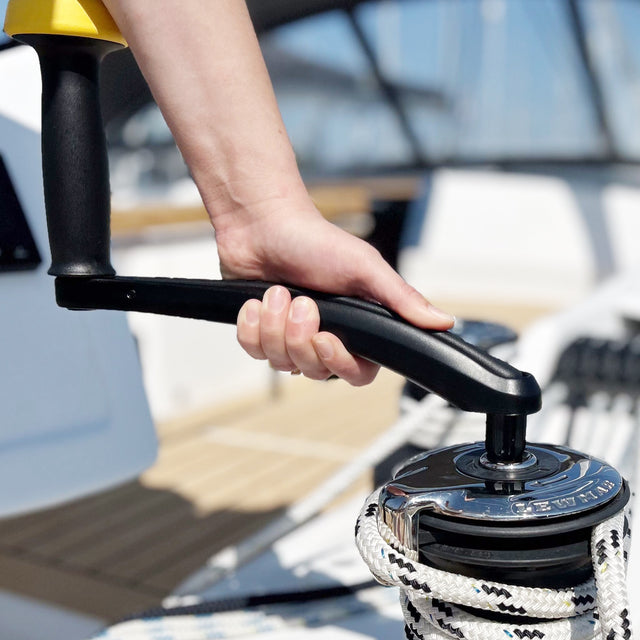 Hand operating a boat winch with a blurred background