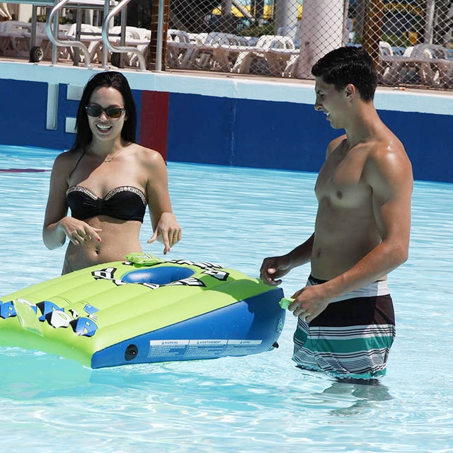 Two people interacting with a colorful inflatable pool toy in a pool.