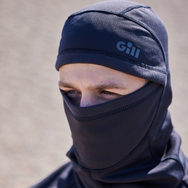 Person wearing a navy balaclava with 'gill' branding on a blurred background