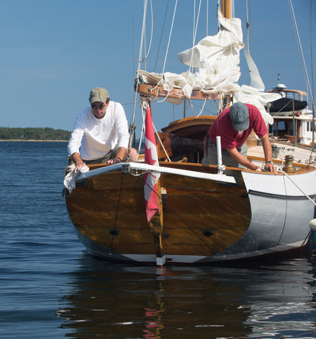 Two people working on wooden boat.