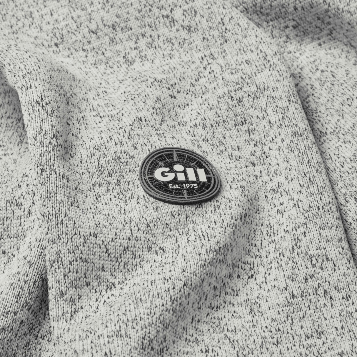 Close-up of a gray textured fabric with a Gill logo patch.