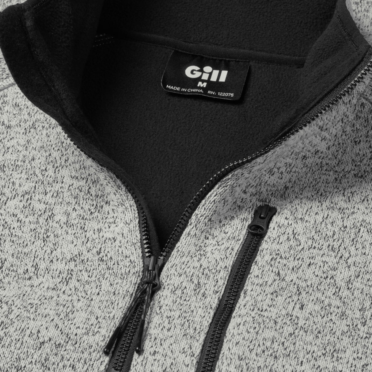 Close-up of a gray and black jacket with a Gill logo on a textured surface