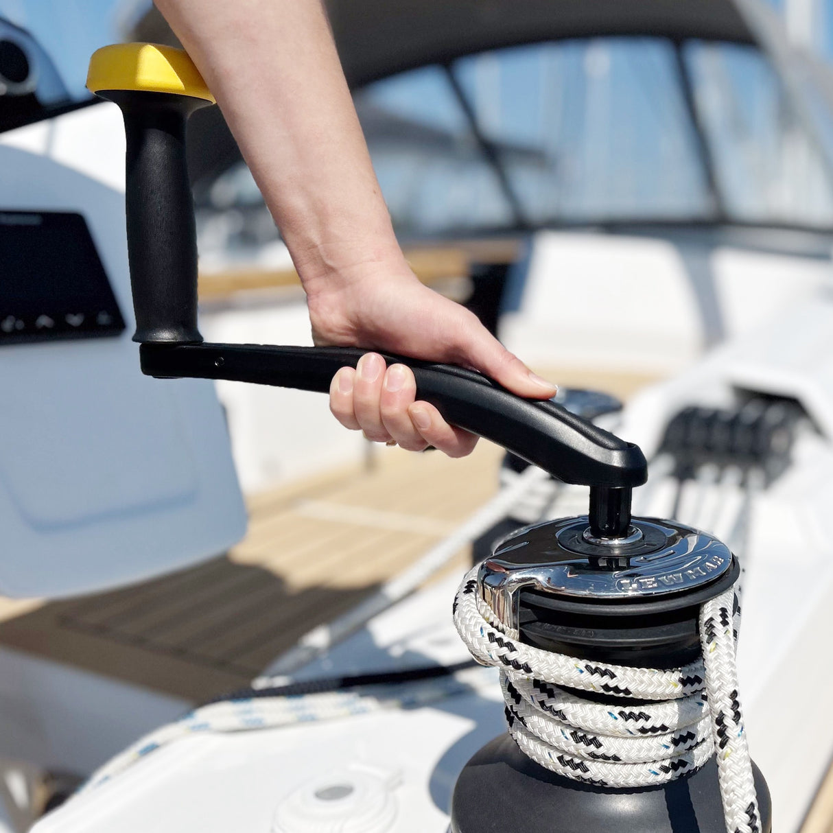 Hand operating a boat's winch with a rope, on a boat deck.