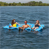 Three people on a blue inflatable raft in a lake with trees in the background
