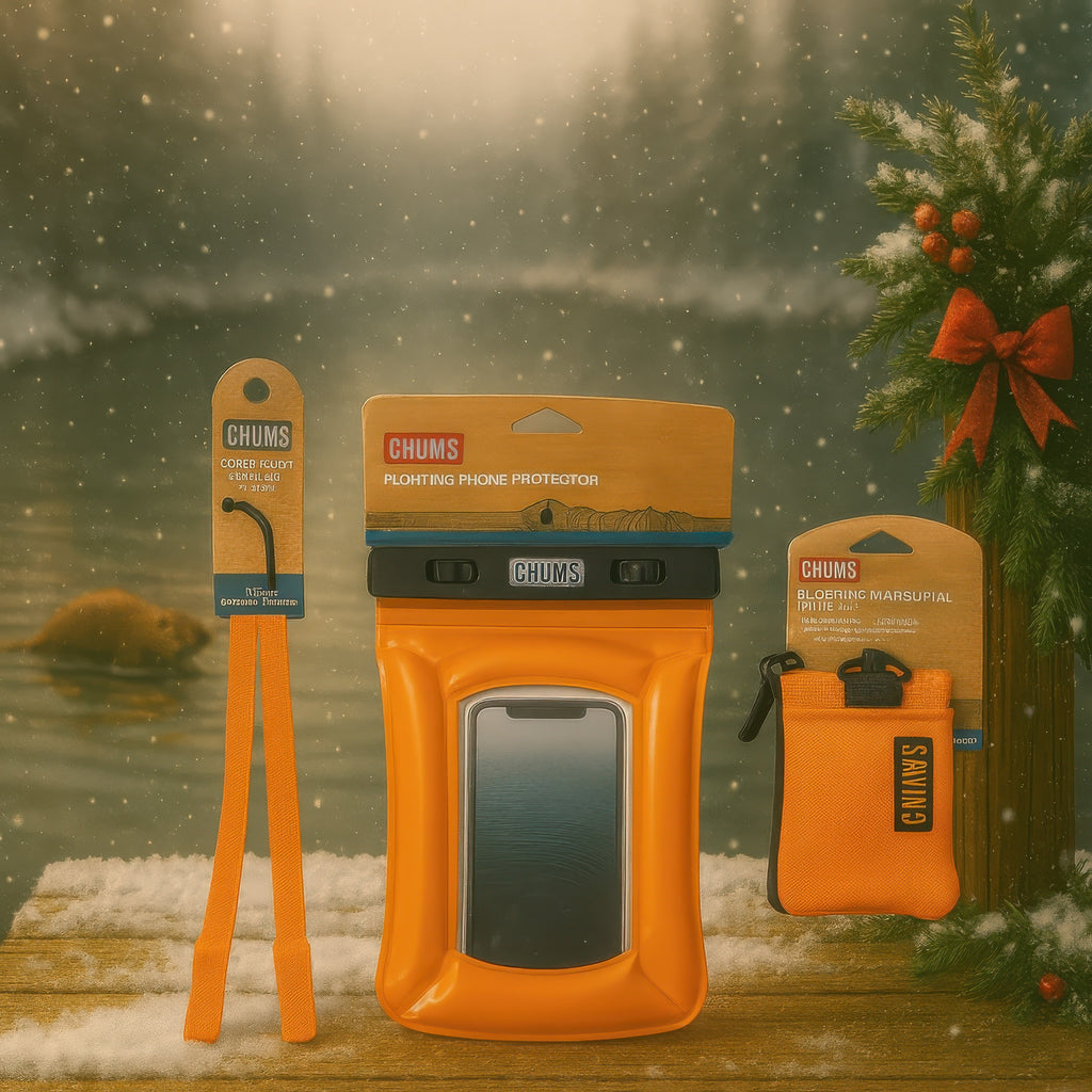 Chums outdoor gear including a phone case, paddle, and pouch against a snowy lakeside background.