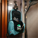 A light blue and black shower wall bag hanging on a shower door in a bathroom, filled with toiletries.