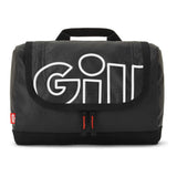 A black quilted GILL travel bag with a large white outlined 'GILL' logo on the front flap, featuring a top carry handle and a small red GILL tag on the left side.