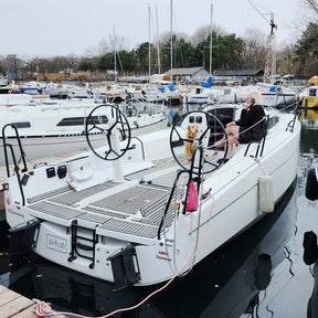 White sailboat docked at a marina with people on board