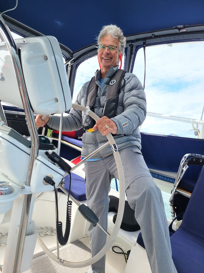 Person steering a boat from the driver's seat with a clear sky background