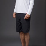 Person wearing black shorts and a white long-sleeve shirt on a gray background