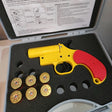 Yellow and red gun-shaped device with gold cartridges in a case
